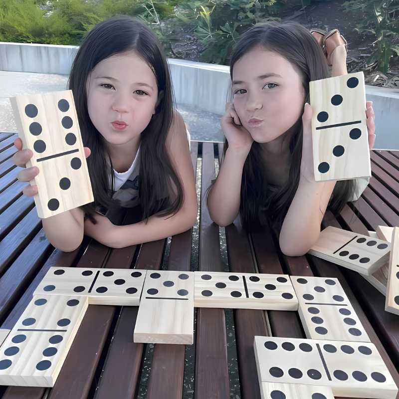two girls holding up wooden giant dominoes