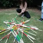 a girl kneeling on grass with many sticks