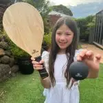 Girl Holding Up A Wooden Bat & Black Ball
