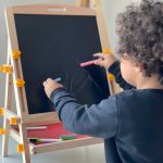 little bot writing a black board with chalk