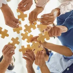 Multiple Hands On A Puzzle Piece Each